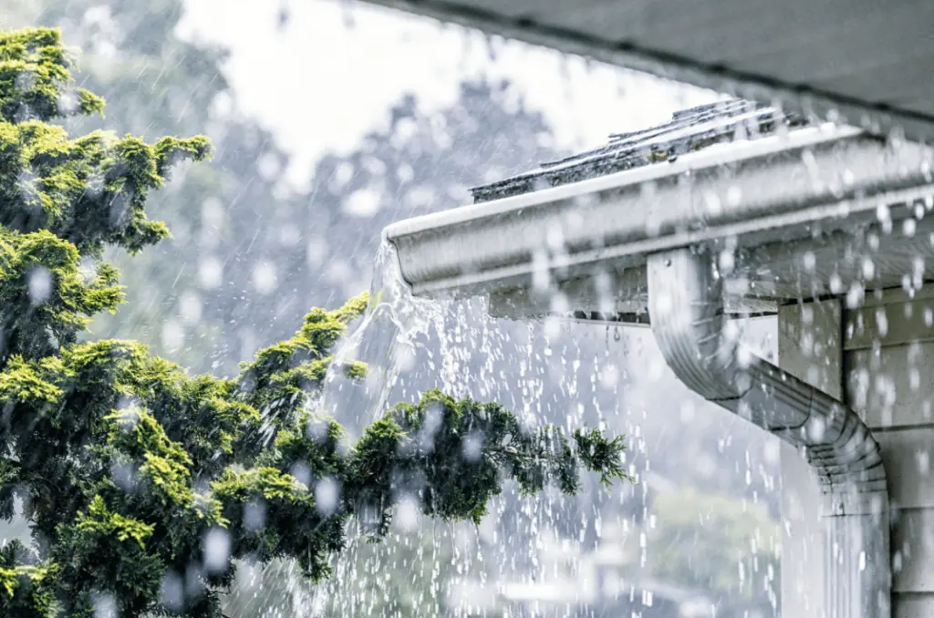Overflowing rain gutter showing signs that professional gutter cleaning services are needed